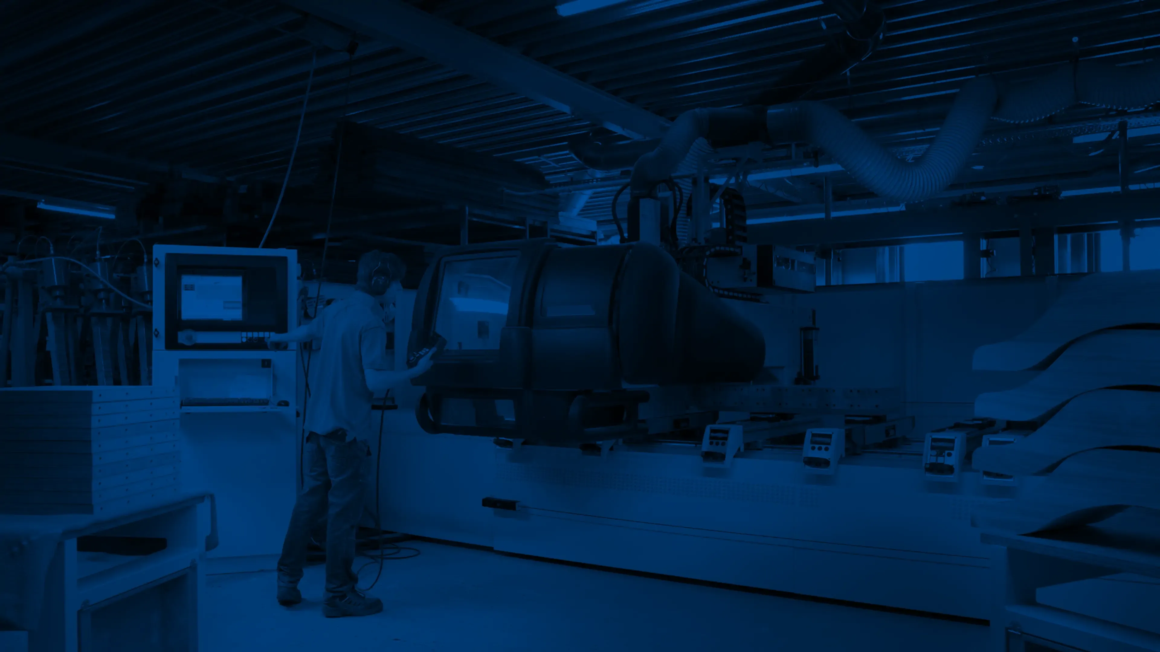 An operator at the control panel of a CNC machining centre in a workshop.