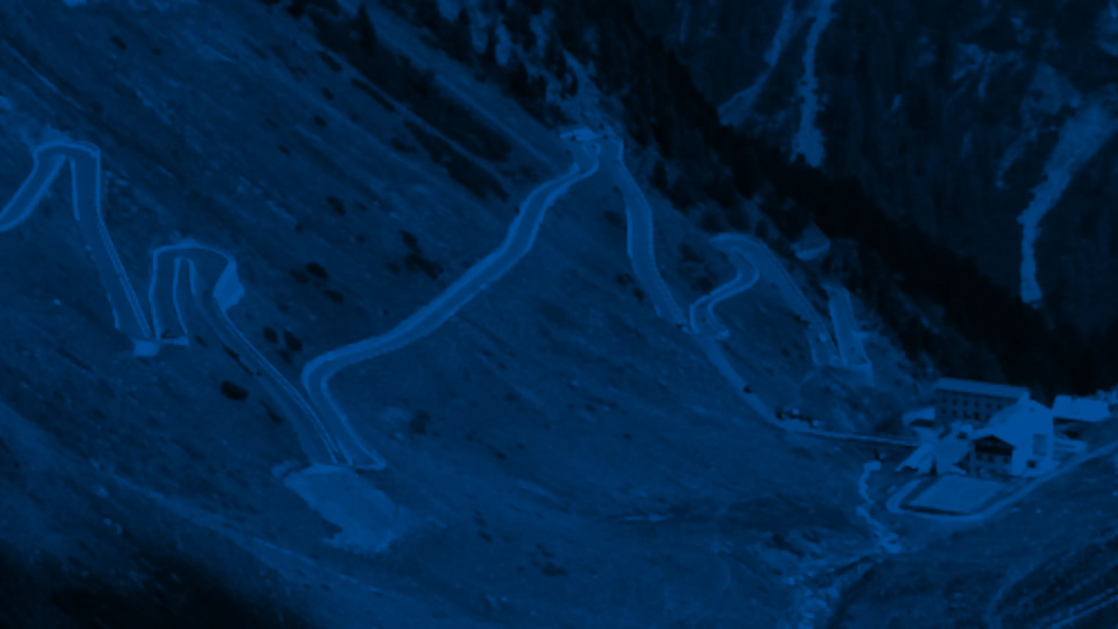 Hairpin bends of an alpine pass road switchbacking up a mountainside.