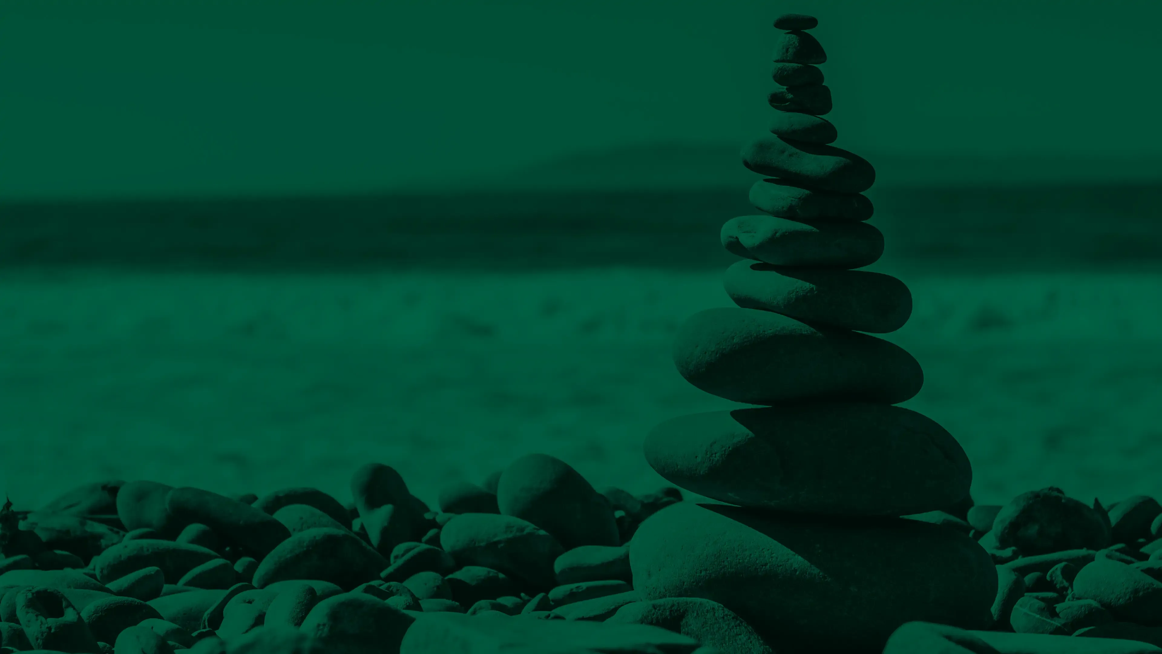 A balanced cairn of smooth stones stacked on a pebble beach.